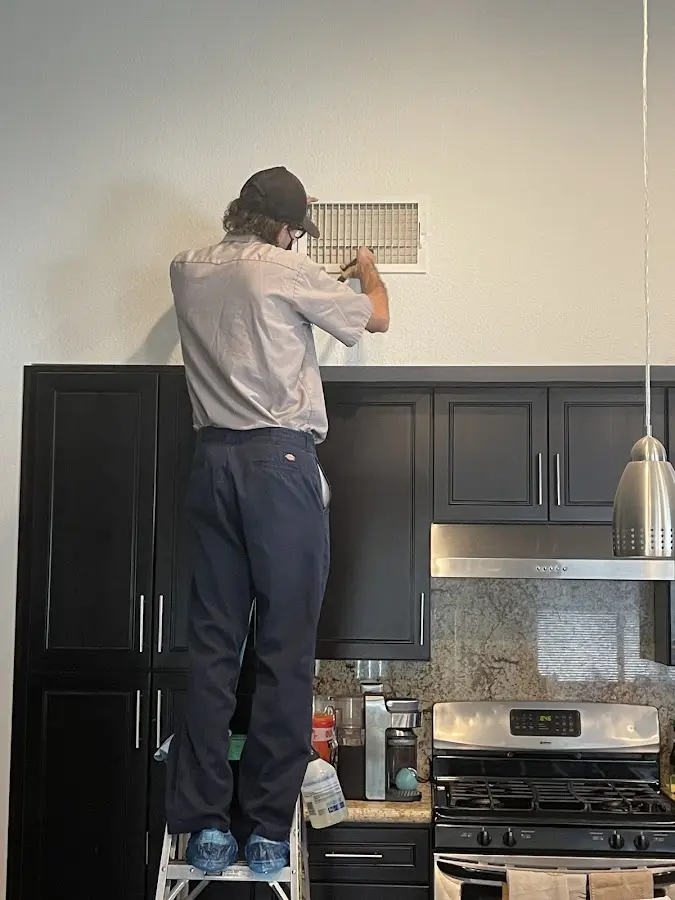 Technician inspecting an air vent during HVAC service in Kailua